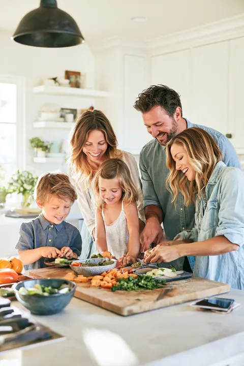 Family of four cooking dinner together in a bright open kitchen
